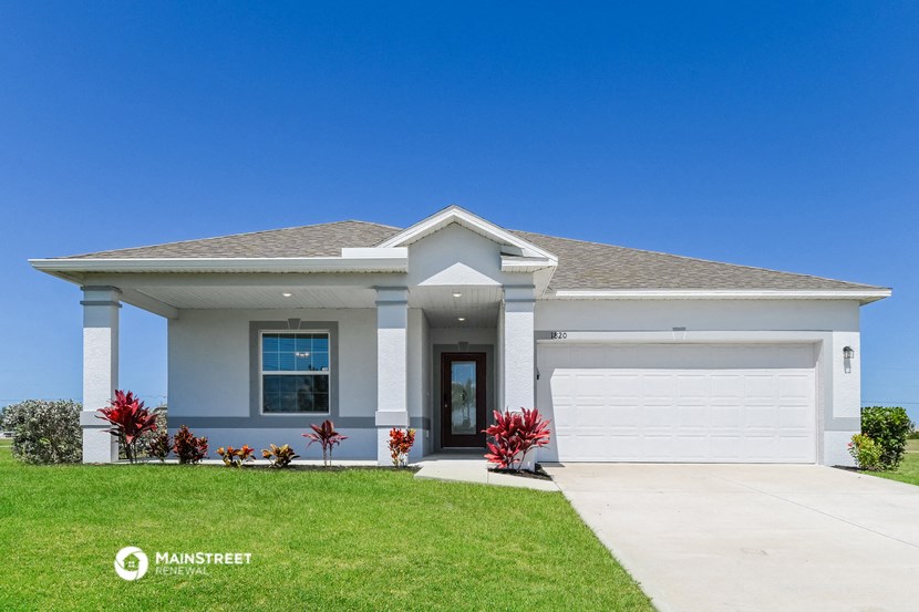 a white house with a garage door and a lawn