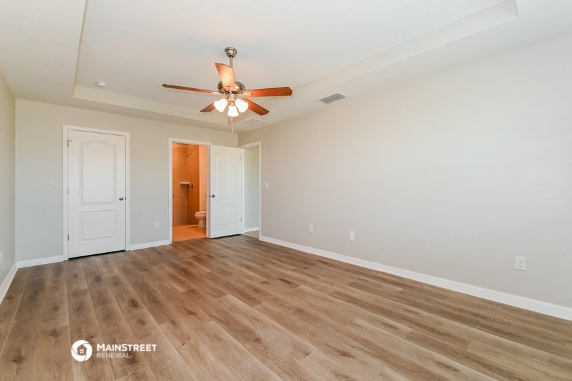 the living room is spacious with hardwood floors and a ceiling fan