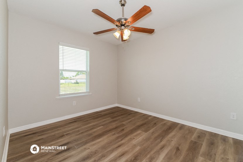 the spacious living room with wood flooring and a ceiling fan