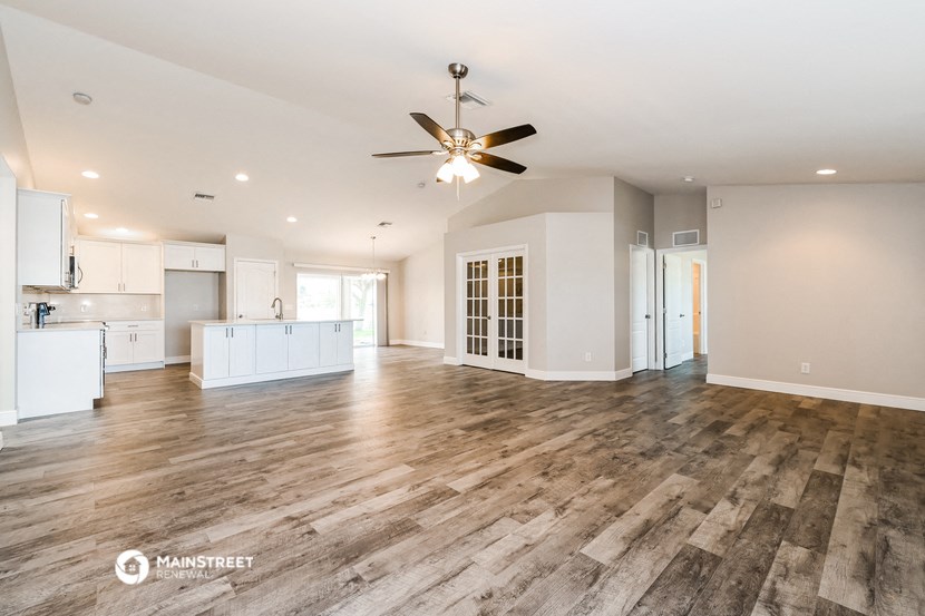an open kitchen and living room with wood flooring and a ceiling fan