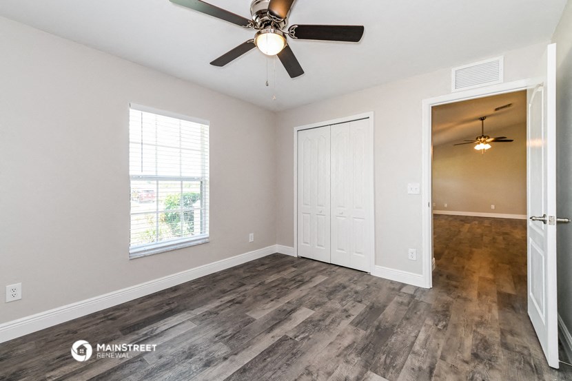 the spacious living room with wood flooring and a ceiling fan