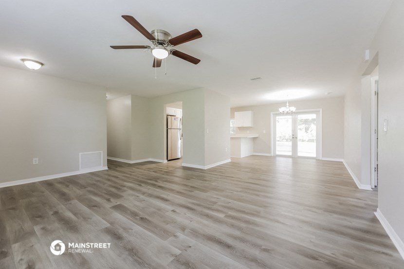 an empty living room with a ceiling fan