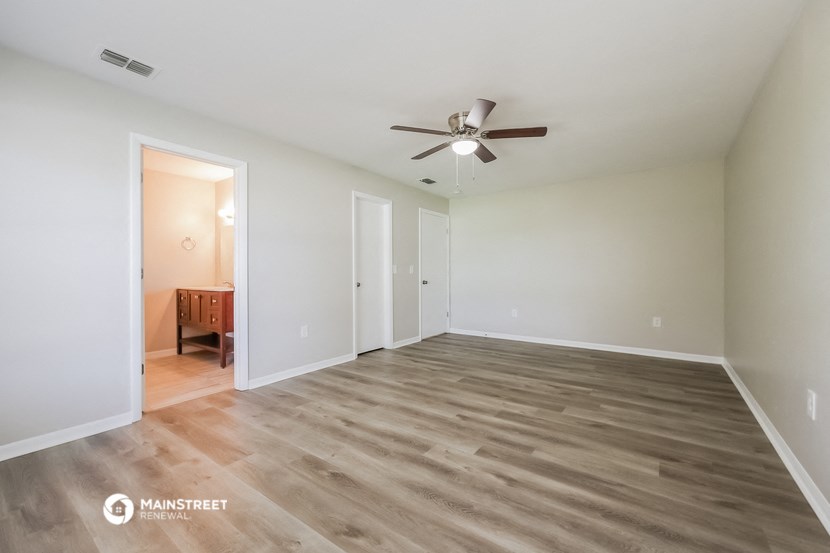 an empty living room with wood flooring and a ceiling fan