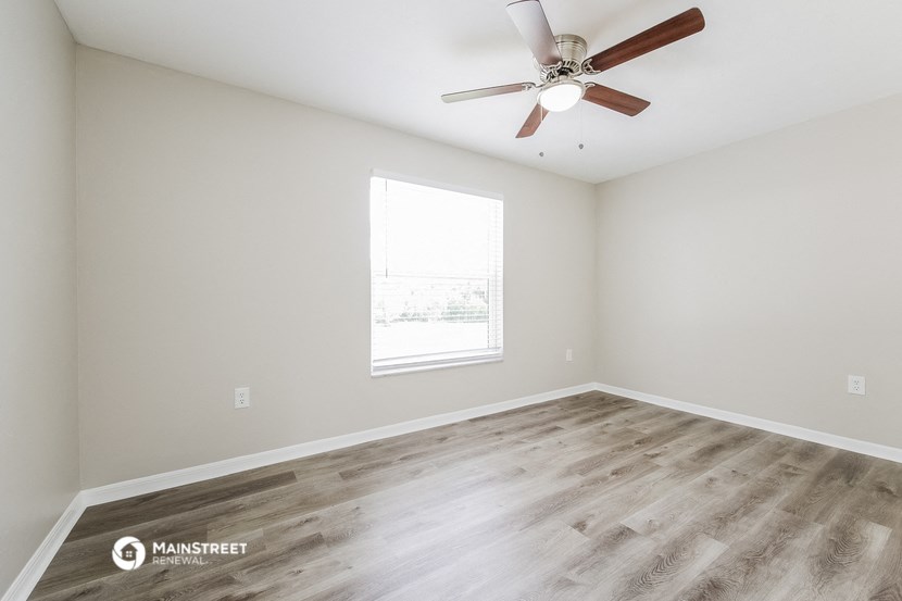 an empty room with a ceiling fan and a window