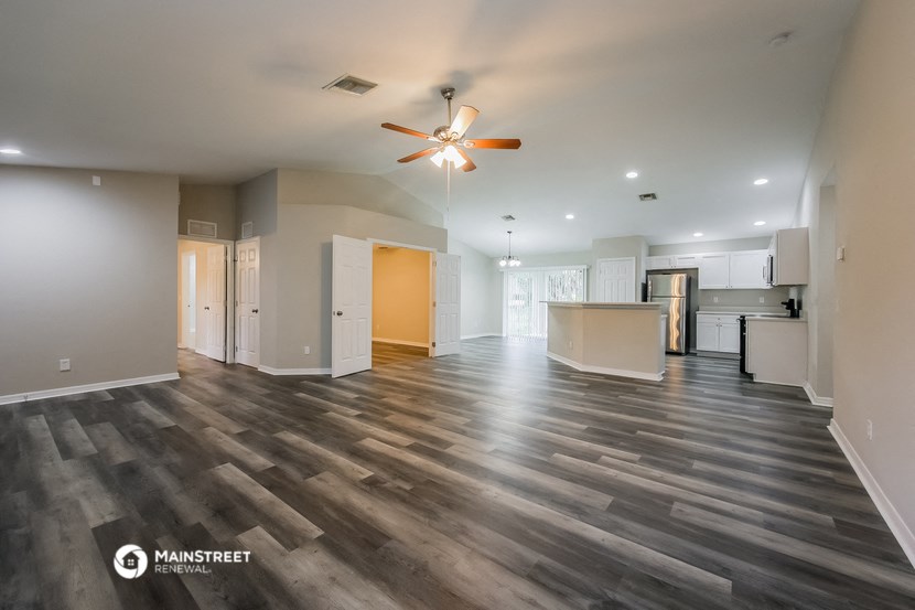 an empty living room and kitchen with a ceiling fan