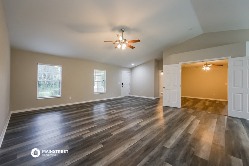 the living room of an empty house with a ceiling fan