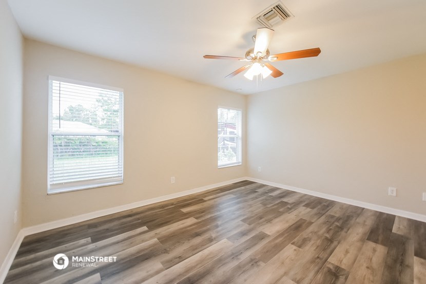 the spacious living room with hardwood floors and a ceiling fan