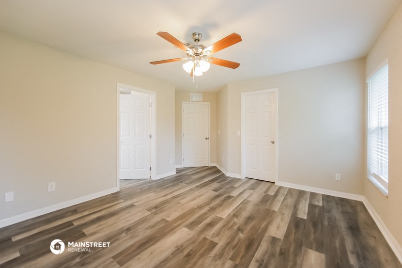 an empty living room with wood flooring and a ceiling fan