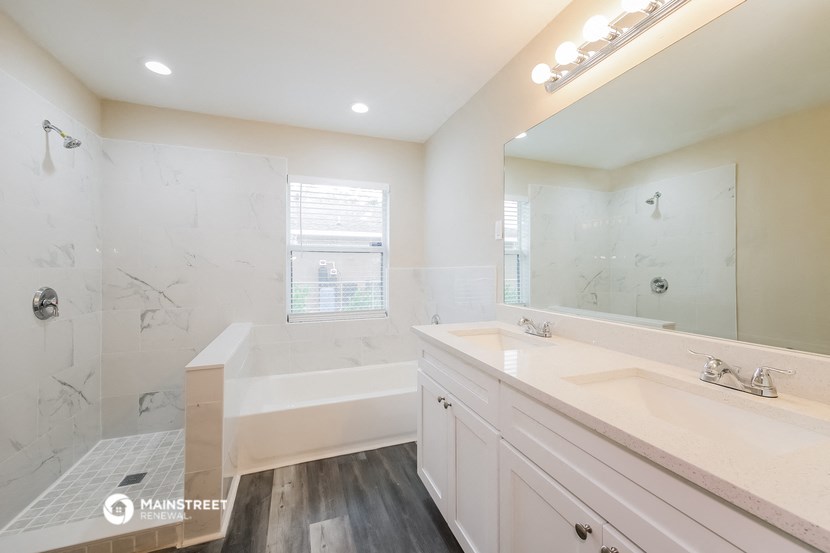 a white bathroom with a tub and a sink and a mirror