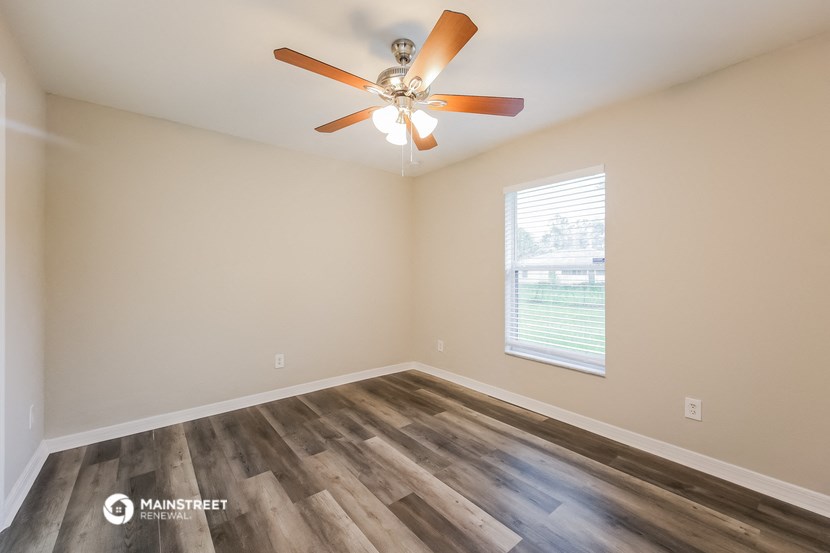 an empty room with a ceiling fan and a window