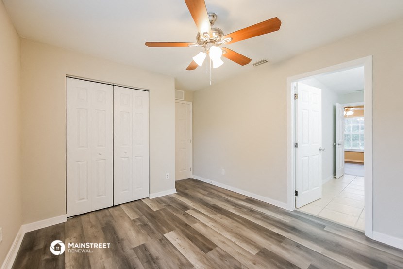 an empty living room with a ceiling fan and a door to a closet