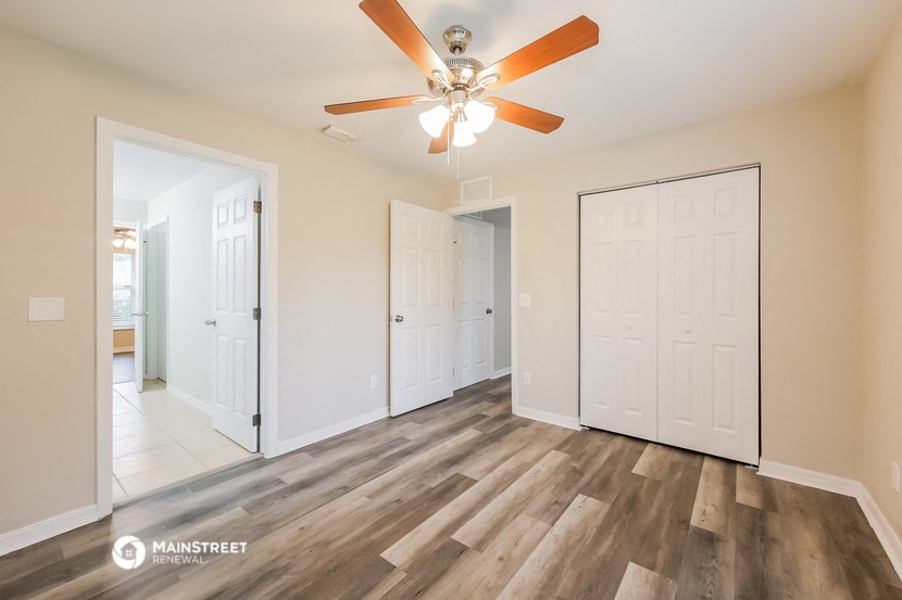 a living room with a ceiling fan and a door to a bathroom