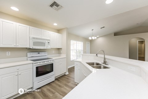 a kitchen with white cabinets and white appliances and white counter tops