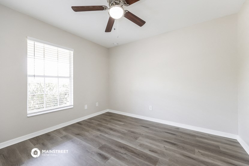 an empty room with a ceiling fan and a window
