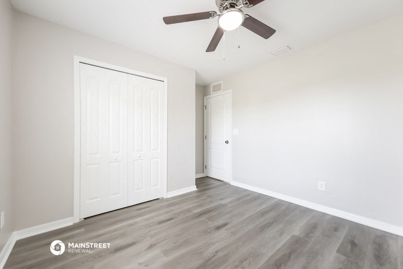 the living room of an apartment with white walls and a ceiling fan