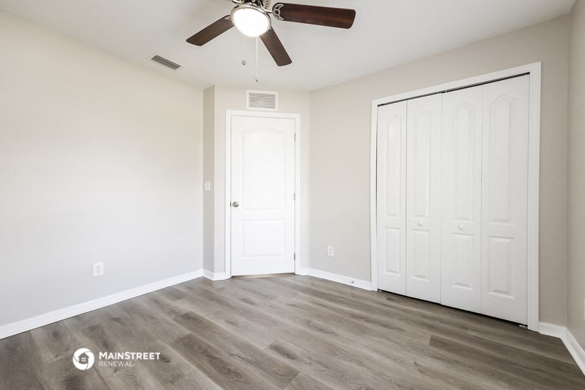 the living room of a new home with white walls and a ceiling fan