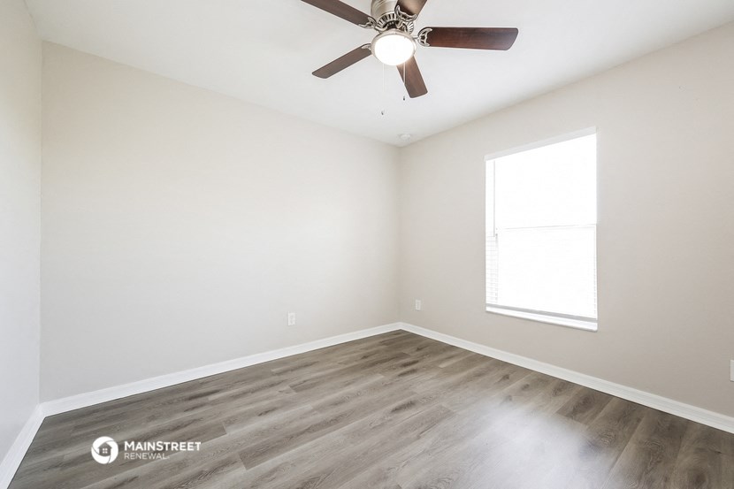 an empty room with a ceiling fan and a window
