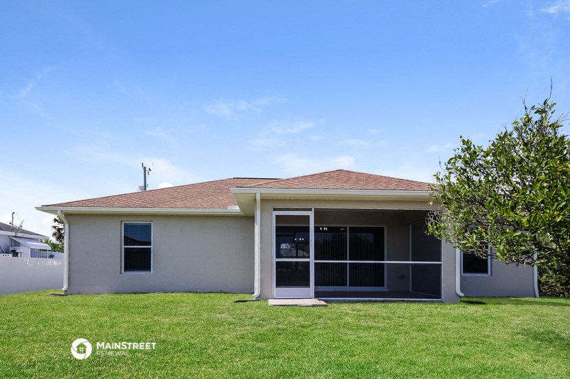 a small white house with a lawn and a tree