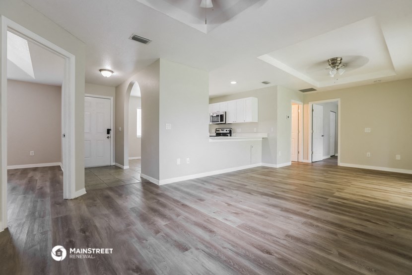 a living room and kitchen with wood flooring and white walls