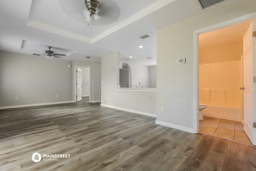 the living room of a new home with wood flooring and a ceiling fan