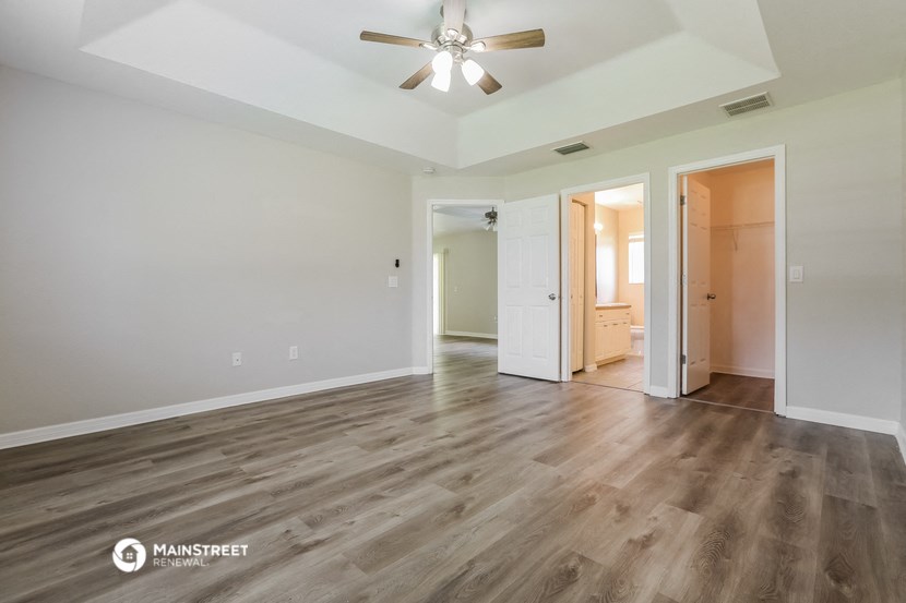 the living room of an empty house with wood flooring and a ceiling fan