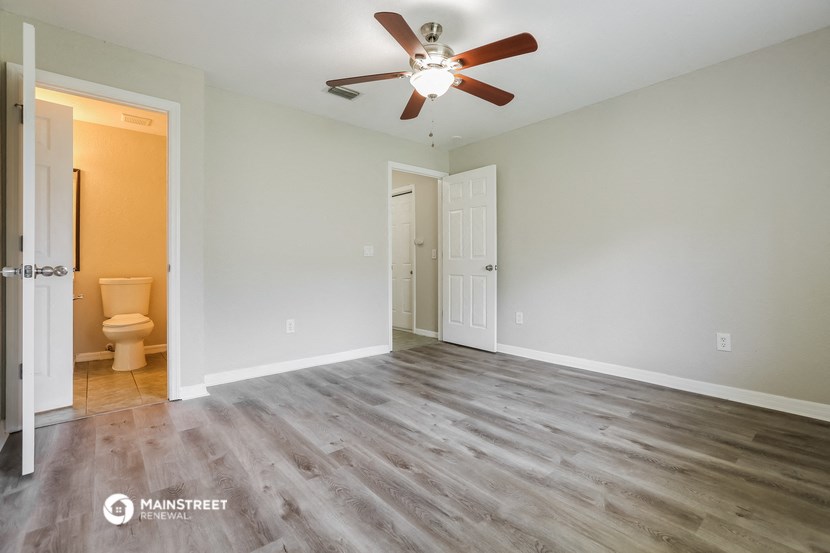 an empty living room with a ceiling fan and a toilet
