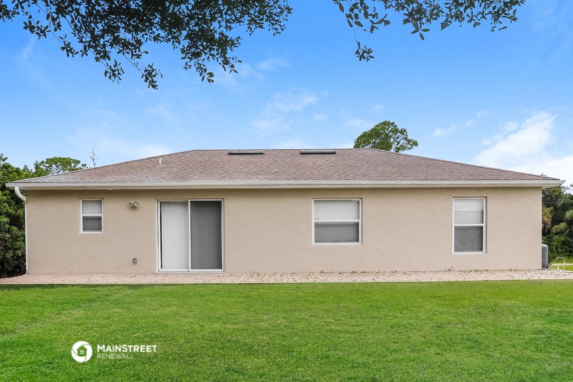 a tan house with a grassy yard and a tree