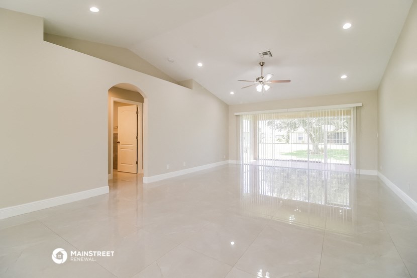 an empty living room with a large window and a ceiling fan