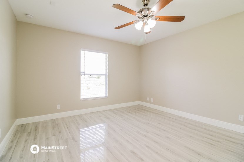 an empty room with a ceiling fan and a window