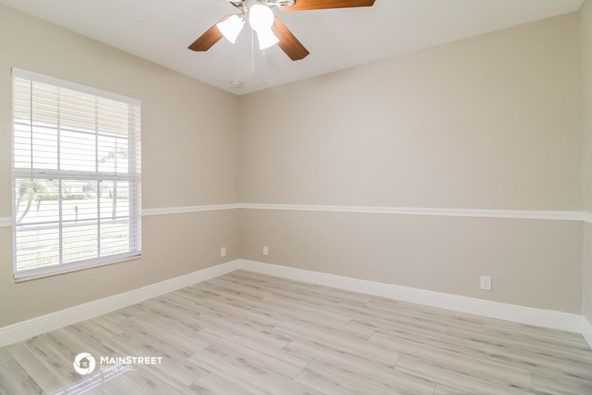 the spacious living room with wood floors and a ceiling fan