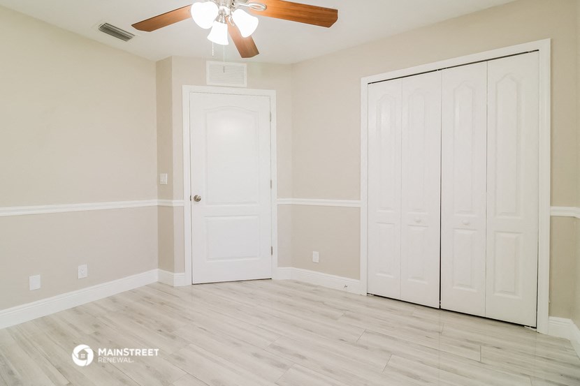 a bedroom with white doors and a ceiling fan