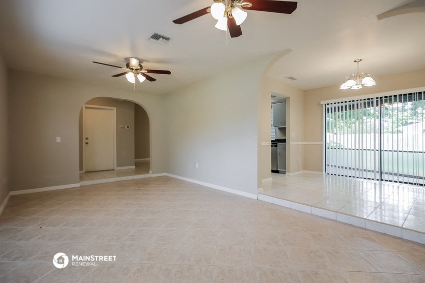 an empty living room with a ceiling fan