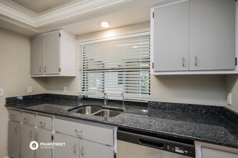 a kitchen with white cabinets and granite counter tops and a sink