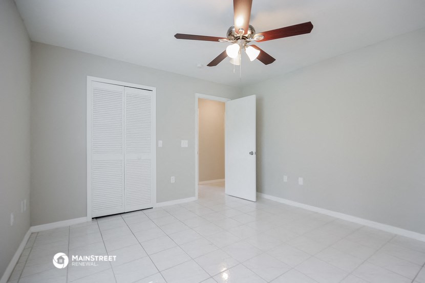 a empty living room with a ceiling fan and a closet