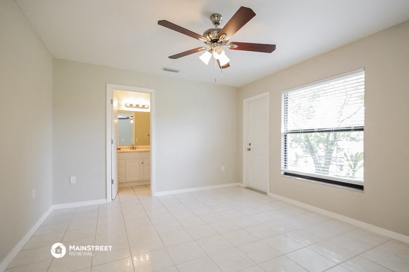 an empty living room with a ceiling fan and a large window