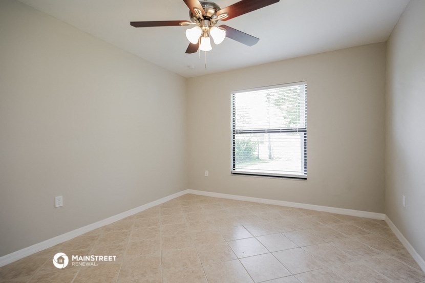 an empty living room with a ceiling fan and a window