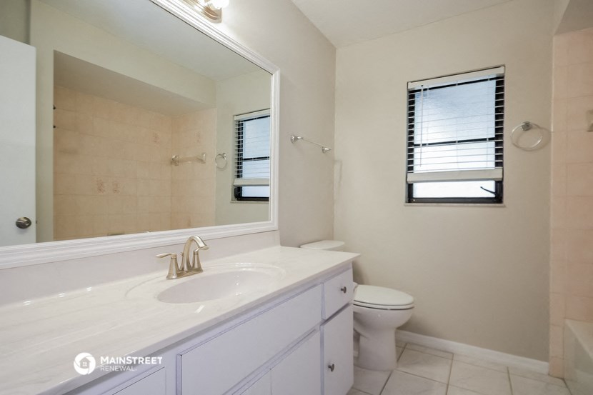 a bathroom with a large mirror and a sink and a toilet