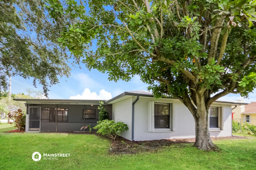 a small white house with a tree in front of it