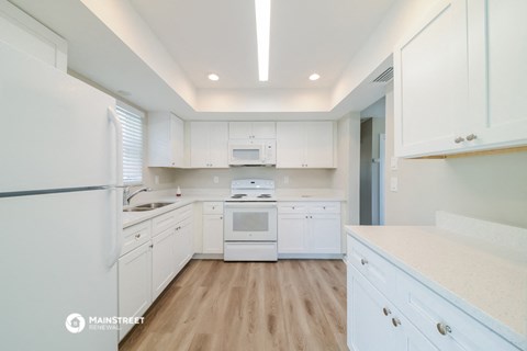 a white kitchen with white cabinets and a white stove and refrigerator