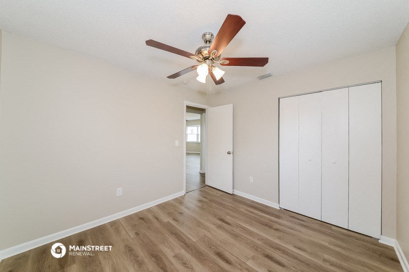the spacious living room with ceiling fan and closet