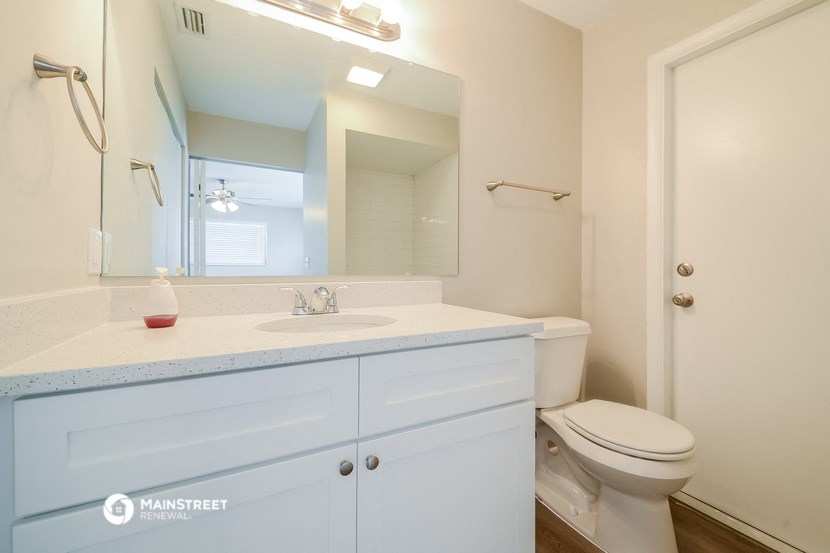 a bathroom with a large mirror and a sink and a toilet