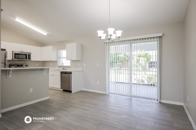 an empty living room with a sliding glass door to a kitchen