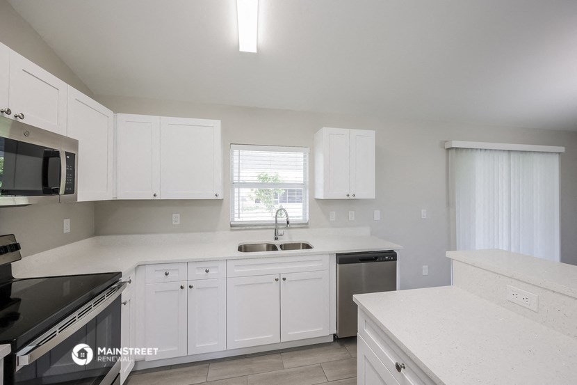 a kitchen with white cabinets and a sink and a window