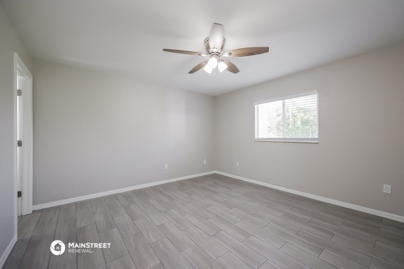an empty room with a ceiling fan and a window