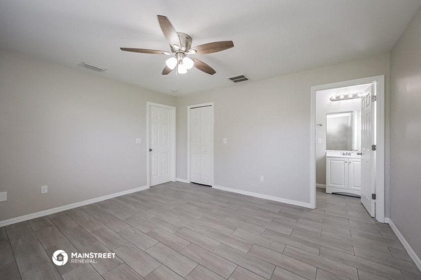 the living room is spacious and has a ceiling fan