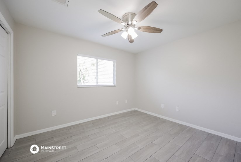 an empty room with a ceiling fan and a window
