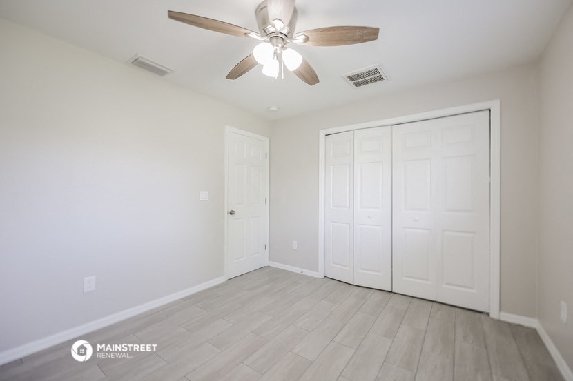 the living room of a new home with white walls and a ceiling fan