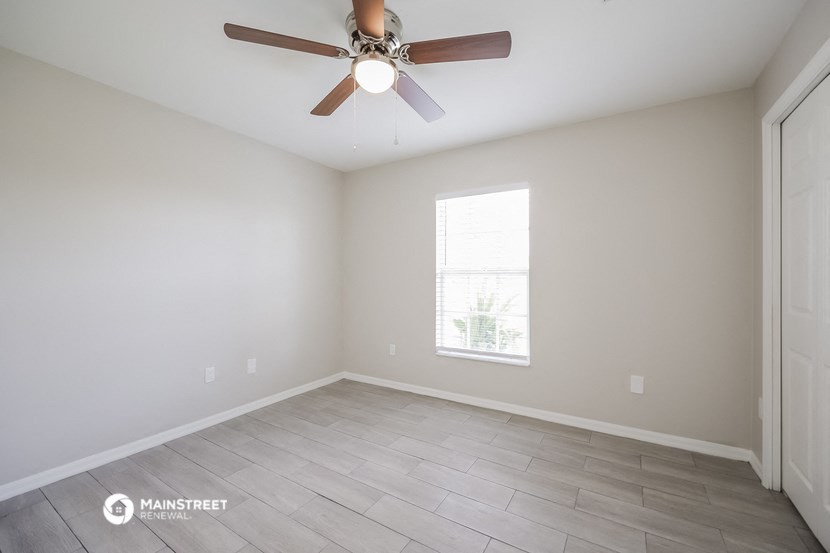 an empty room with a ceiling fan and a window