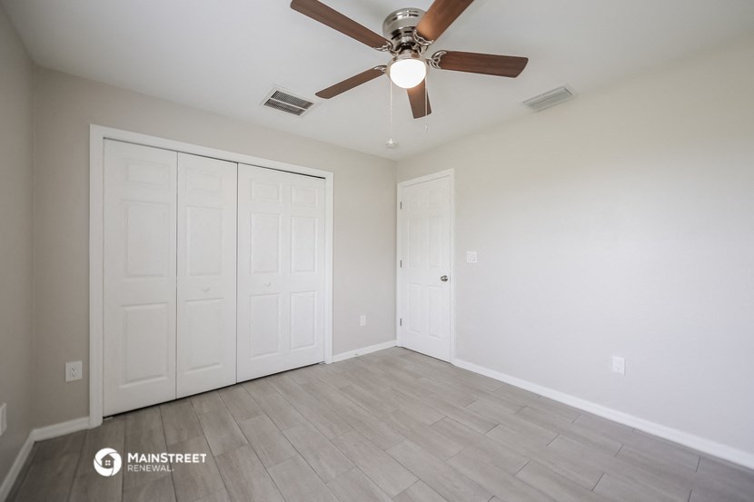 the spacious living room with two closets and a ceiling fan