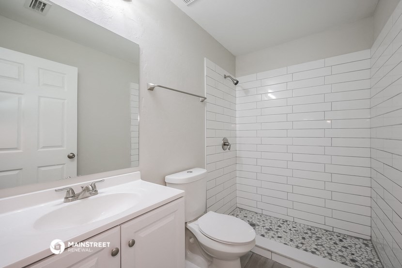a white bathroom with white subway tiles and a white toilet and sink